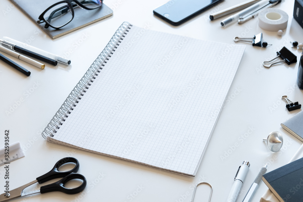 White office desk table with blank notebook and other office supplies. White office desk table with blank notebook and other office supplies.