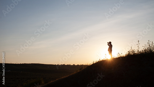 Senior man looking at the horizon in the field on top of a hill in backlight.