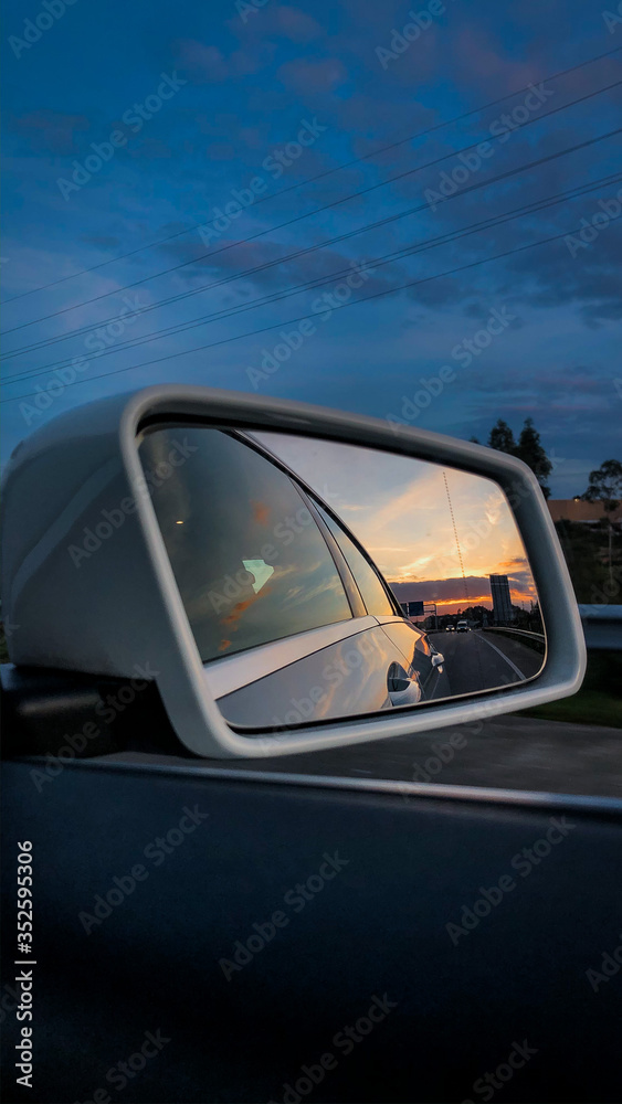 Reflexo do pôr-do-sol no espelho de um carro