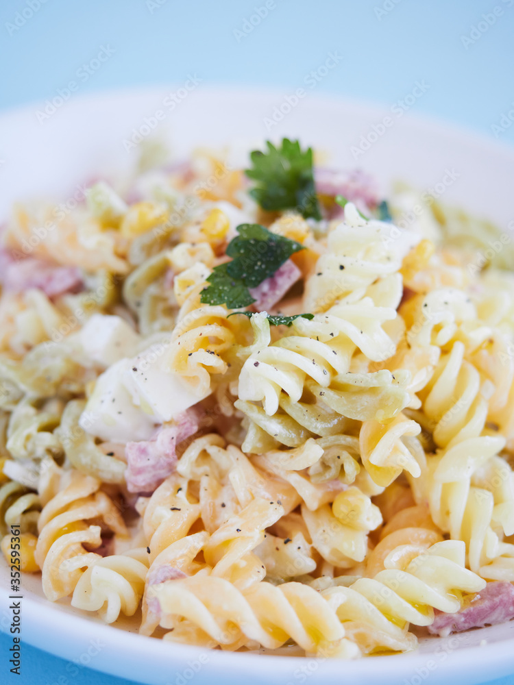 close up view pasta salad with corn, cheese and jam, parsley on top, vertical close up view pasta salad with corn, cheese and jam, parsley on top, vertical
