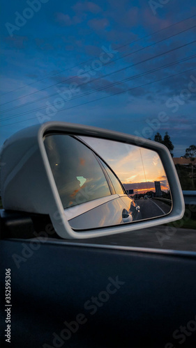 Reflexo do pôr-do-sol no espelho de um carro