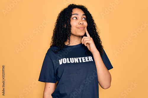 Young african american curly woman doing volunteering wearing volunteer t-shirt serious face thinking about question, very confused idea © Krakenimages.com