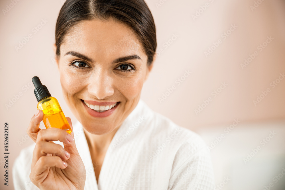 Happy pretty female holding bottle with cosmetic