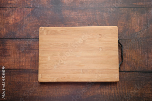 Top view of wooden chopping board on gray background .