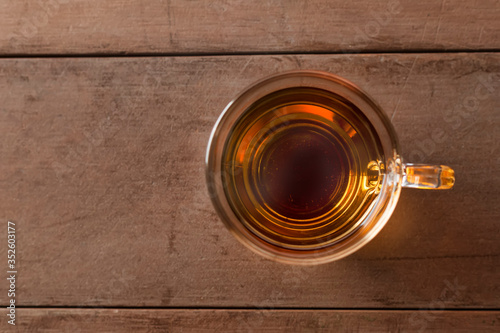 Close up top view hot tea cup on wood table . hot tea in handle glass with copy space for text or design.