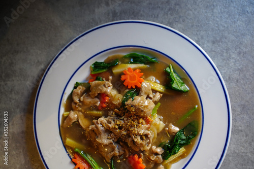 Fried noodles with pork and kale in gravy sauce on white plate, top view of fired noodles