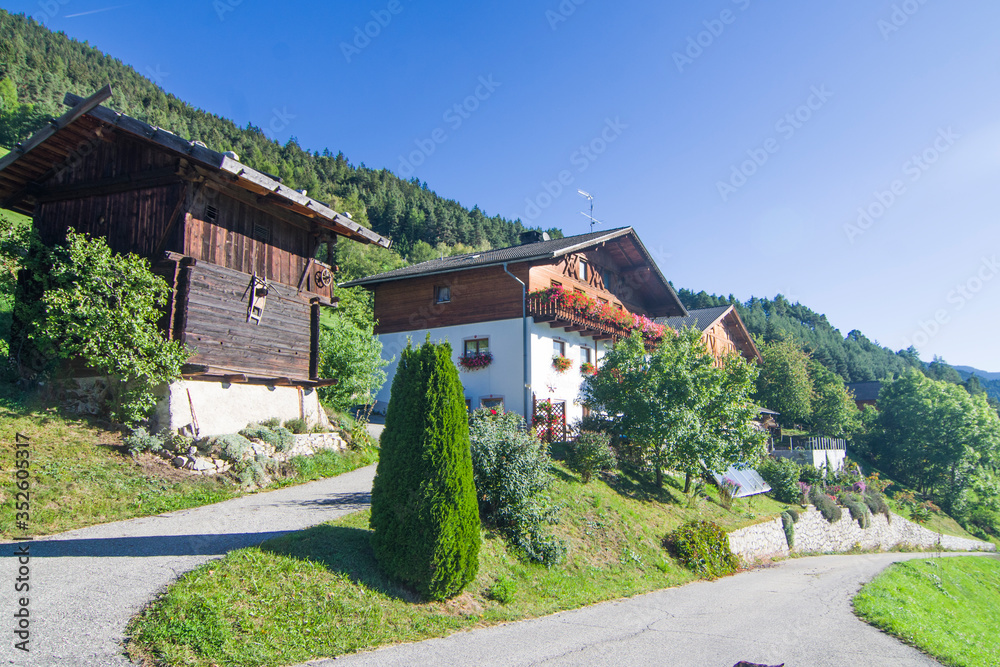 typical mountain building in stone, white plaster and wood and with colorful flowers
