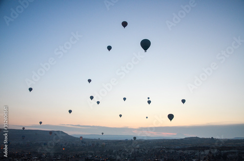 Hot air balloons at sunrise flying in the sky along valleys at Cappadocia of Goreme, Turkey 