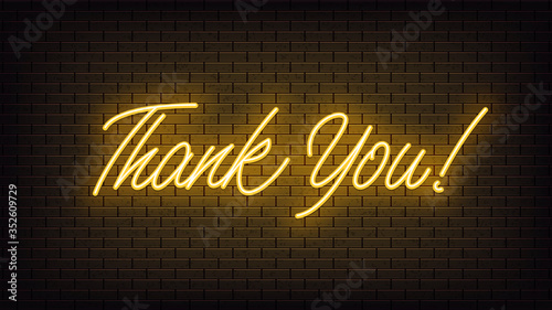 Yellow neon Thank You, lettering. Neon text of Thank You on black brick background