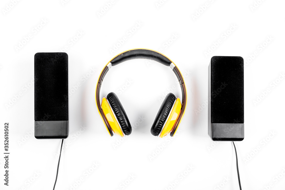 headphones and black speakers on white table top-down headphones and black speakers on white table top-down