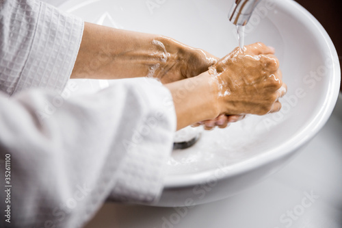 Woman washing hands in sink in bathroom