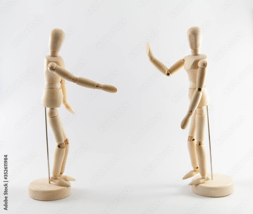 Wooden puppets on white background with social distancing concept. Gesture of one puppet refusing to shake hand. Concept of coronavirus infection prevention. Wooden puppets on white background with social distancing concept. Gesture of one puppet refusing to shake hand. Concept of coronavirus infection prevention.