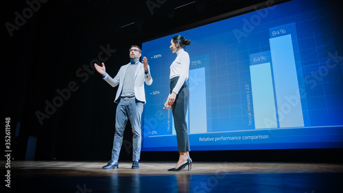 Fotografía On Stage, Successful Female CEO and Male COO Speakers Present Company's New Product, Show Infographics, Statistics on Big Screen, Talk About Growth