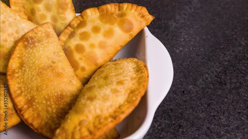 Great photo of Brazilian pastry (pastel), traditional dish of Brazilian cuisine in a dish on a black granite background. photo