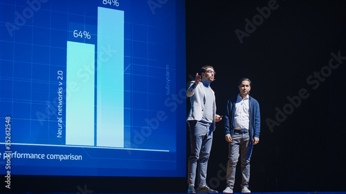 Startup CEO and Chief Developer Stand on Stage and Present New Product. Speakers Lead Lecture on Business, Science, Technology, Entrepreneurship, Health, Ecology, Leadership and all Things Digital © Gorodenkoff