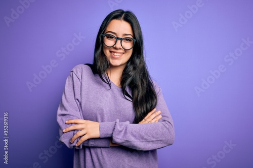 Young brunette woman wearing glasses over purple isolated background happy face smiling with crossed arms looking at the camera. Positive person.