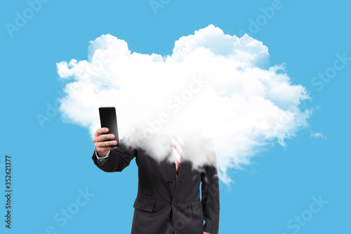 Businessman with his head in the clouds consulting with the mobile the economic crisis on blue background. Surreal concept