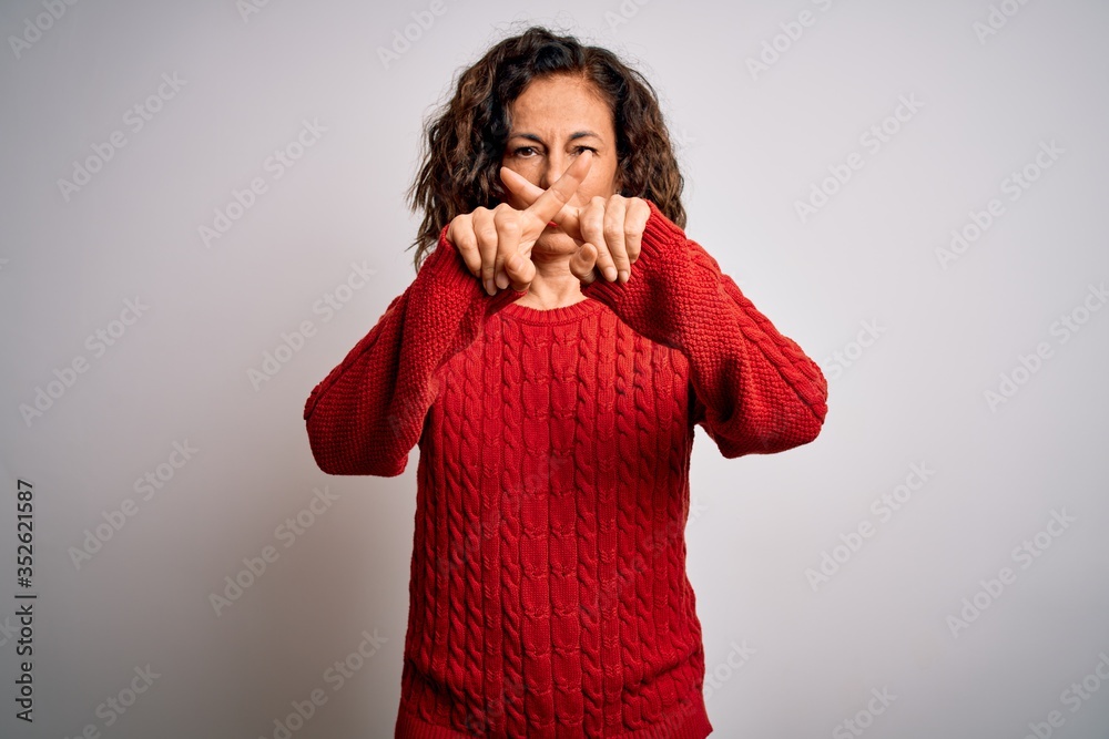 Middle age brunette woman wearing casual sweater standing over isolated white background Rejection expression crossing fingers doing negative sign Middle age brunette woman wearing casual sweater standing over isolated white background Rejection expression crossing fingers doing negative sign