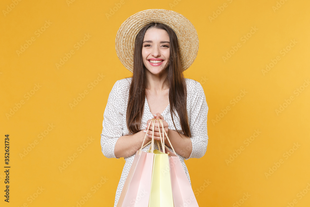 Smiling young brunette woman girl in white dress hat posing isolated on yellow background studio portrait. People lifestyle concept. Mock up copy space. Hold package bag with purchases after shopping. Smiling young brunette woman girl in white dress hat posing isolated on yellow background studio portrait. People lifestyle concept. Mock up copy space. Hold package bag with purchases after shopping.