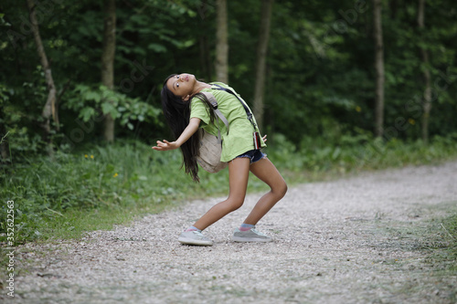 A cute little girl poses like a dancer in the forest