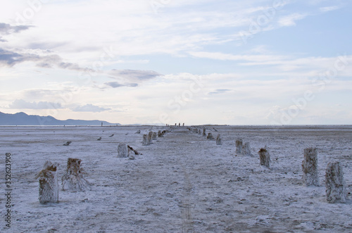 Looking down the long walkway of the old great salt lake salty pier post ruins in the evening light. 