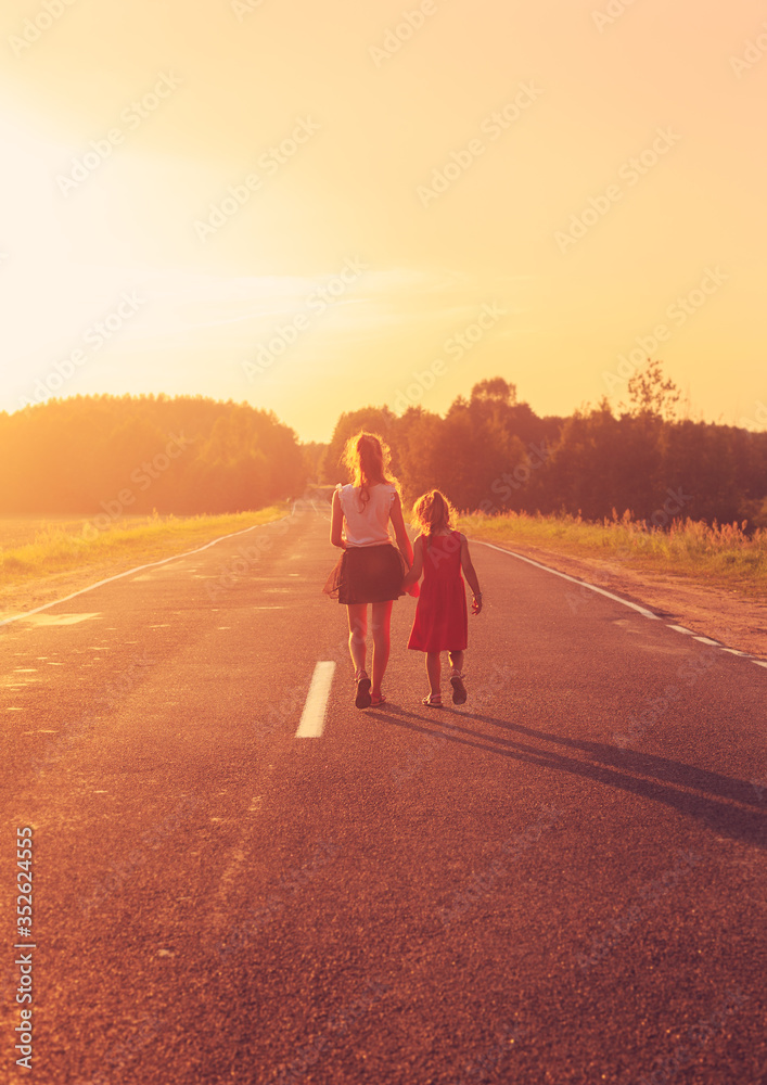 Silhouette of two little girls walking on the road . Sisters enjoyed summer day over blurred summer nature. Concept People and nature.