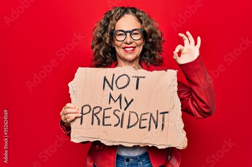 Photo Middle age woman asking for democracy holding banner with not my president messa