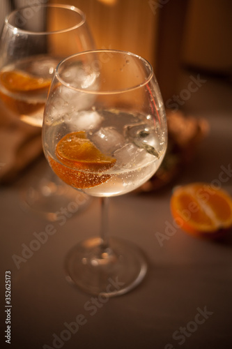 Glass of gin and tonic with orange and sage in warm light