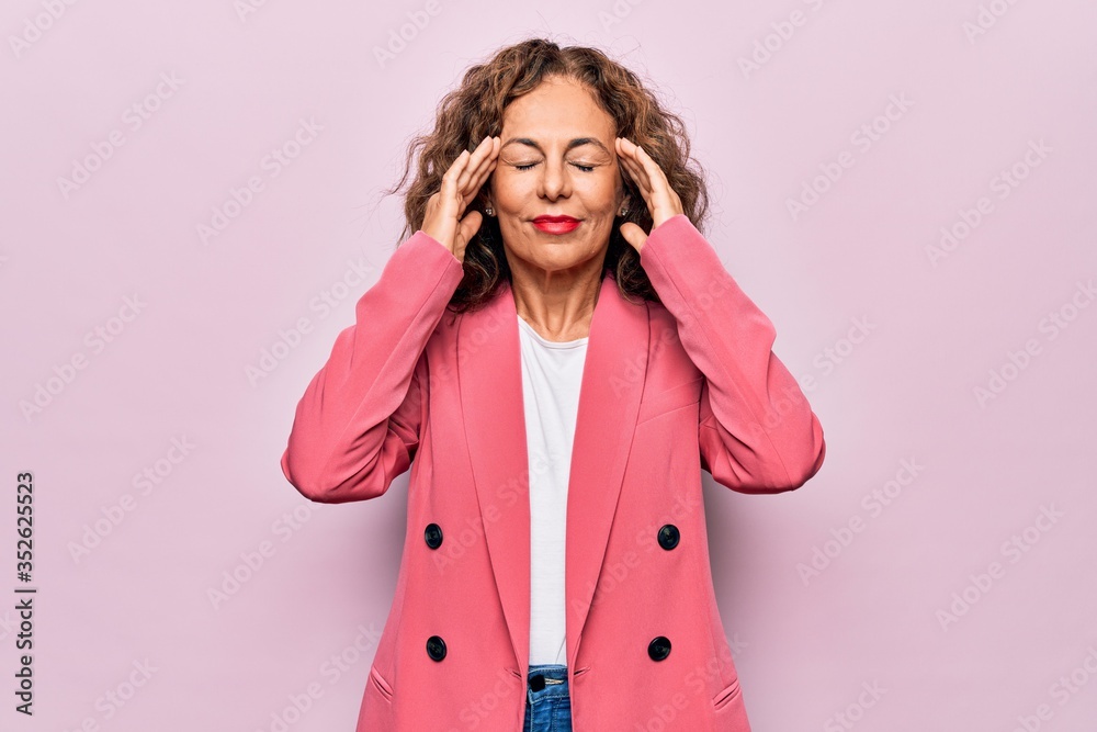 Middle age beautiful businesswoman wearing jacket standing over isolated pink background with hand on head, headache because stress. Suffering migraine. Middle age beautiful businesswoman wearing jacket standing over isolated pink background with hand on head, headache because stress. Suffering migraine.