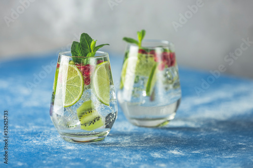 Detox water or martini tonic cocktail with kiwi, lime and ice, decoration pomegranate and mint. Summer fresh lime soda cocktail, selective focus.