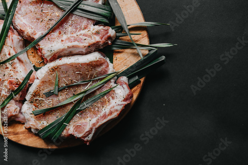 Raw meat, lie on a cutting board in spices, rosemary, thyme and marinade, background image with copy space, top view. concept of marinating meat