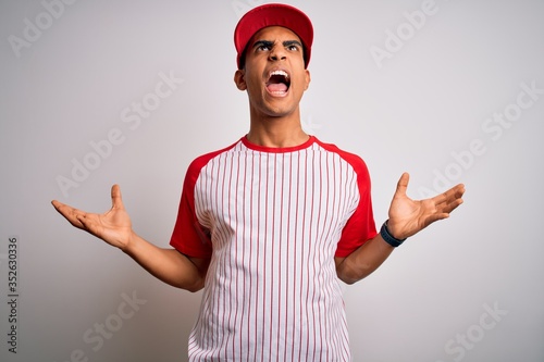 Canvas Print Young handsome african american sportsman wearing striped baseball t-shirt and cap crazy and mad shouting and yelling with aggressive expression and arms raised