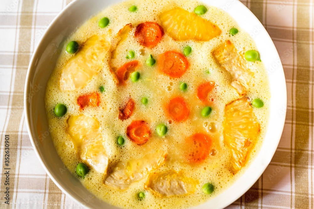 Creamy vegetable soup from celery and carrot with green pea, closeup.