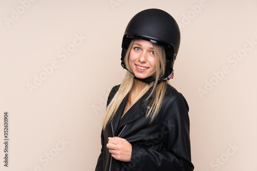 Young blonde woman with a motorcycle helmet over isolated background