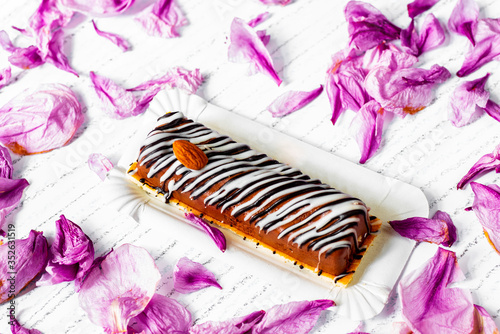 Fototapeta Naklejka Na Ścianę i Meble -  Striped nougat cake on background with pink petals.