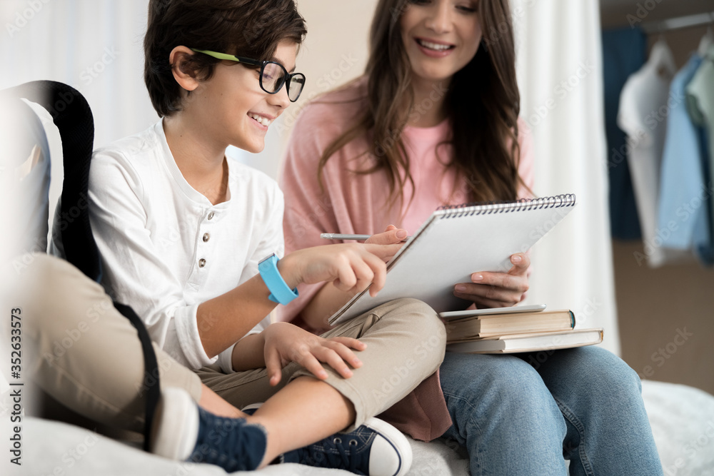 Pleased schoolchild and his mother doing homework Pleased schoolchild and his mother doing homework