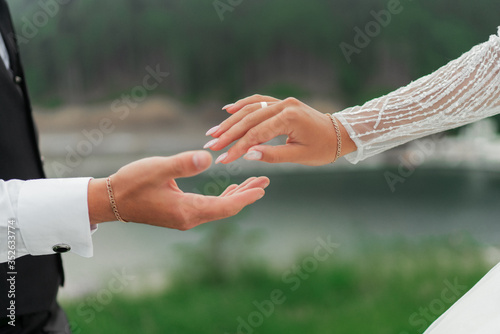 She said yes concept. Suited up man fiance groom hands stylish platinum white gold proposal engagement wedding ring to his bride. Close up, top view, copy text space.