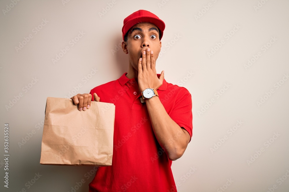 Young handsome african american delivery man holding paper bag with takeaway food cover mouth with hand shocked with shame for mistake, expression of fear, scared in silence, secret concept Young handsome african american delivery man holding paper bag with takeaway food cover mouth with hand shocked with shame for mistake, expression of fear, scared in silence, secret concept