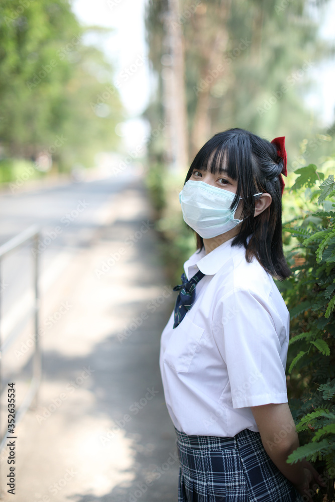Naklejka premium Asian school girl with mask in urban city on tree background