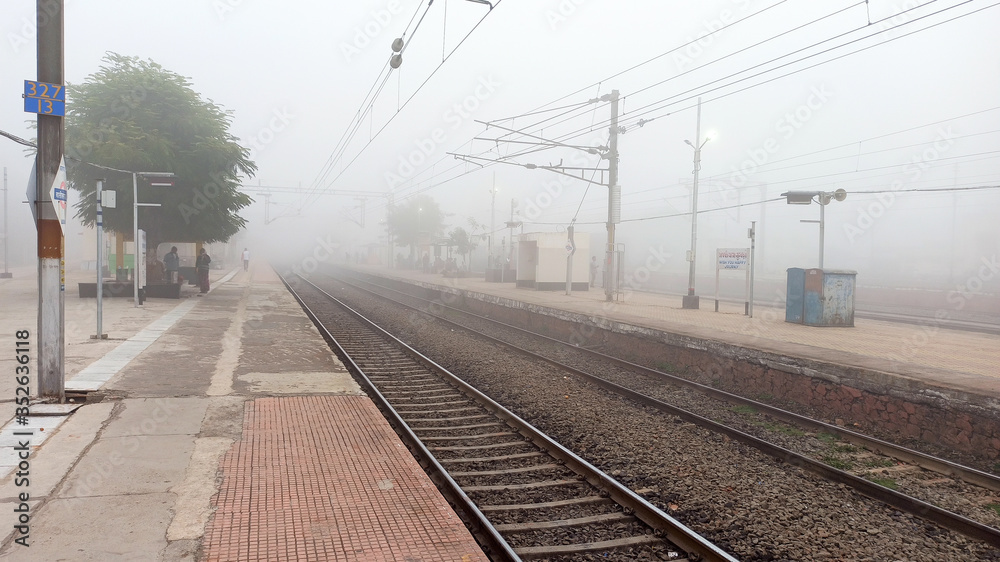 empty rail track from station in early morning fog