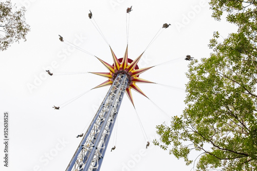 The carousel is higher than the trees with a grey sky in the background. Bottom view