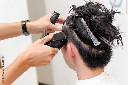 Foto バリカンで若い男性のサイドのヘアを刈り上げるシーン