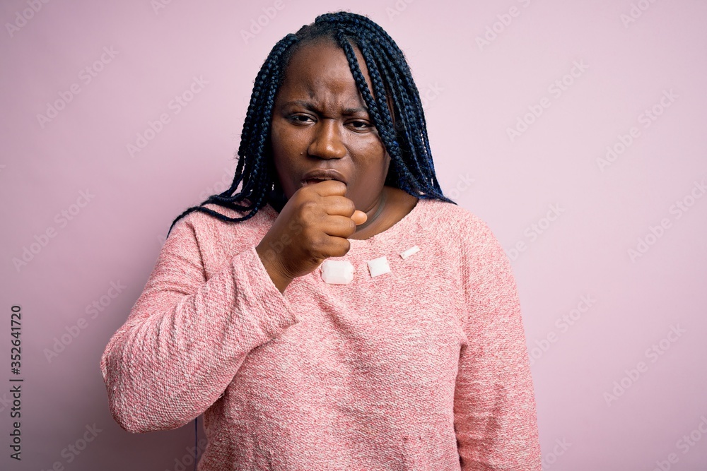 African american plus size woman with braids wearing casual sweater over pink background feeling unwell and coughing as symptom for cold or bronchitis. Health care concept. African american plus size woman with braids wearing casual sweater over pink background feeling unwell and coughing as symptom for cold or bronchitis. Health care concept.