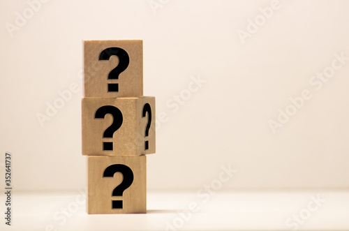 Four wooden blocks with black question marks. - Image