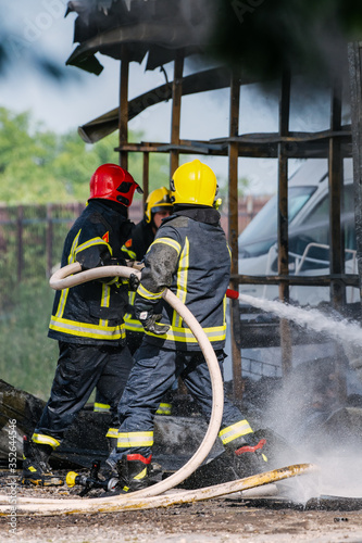 Two firefighters spraying high pressure water to fire.