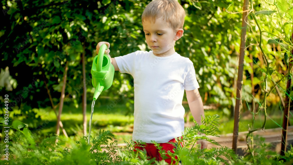 Portrait of cute little boy with watering can in garden Portrait of cute little boy with watering can in garden