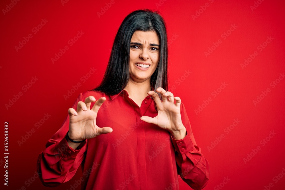 Young beautiful brunette woman wearing casual shirt standing over red background disgusted expression, displeased and fearful doing disgust face because aversion reaction. With hands raised Young beautiful brunette woman wearing casual shirt standing over red background disgusted expression, displeased and fearful doing disgust face because aversion reaction. With hands raised