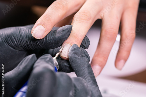 Process manicure close-up. Preparation for hardware manicure. Beautician in rubber gloves cuts the cuticle and processes nails. © satura_