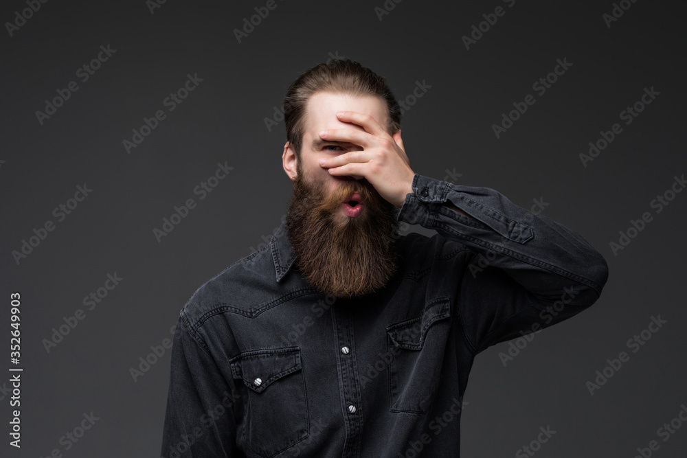 Young man with hand on face covering eyes for surprise standing over isolated gray background . Blind concept.