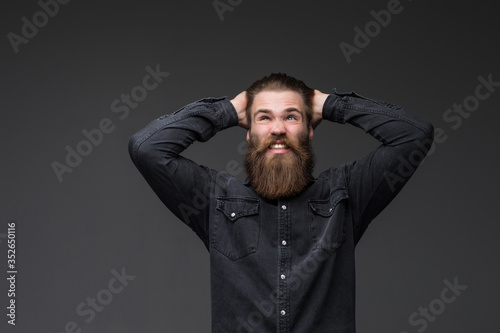 Bearded young hipster man in rage shouting loudly with mouth opened on gray background. © F8  \ Suport Ukraine